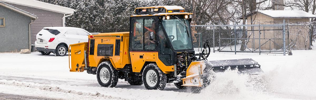 Trackless machine with snow sweeping brush